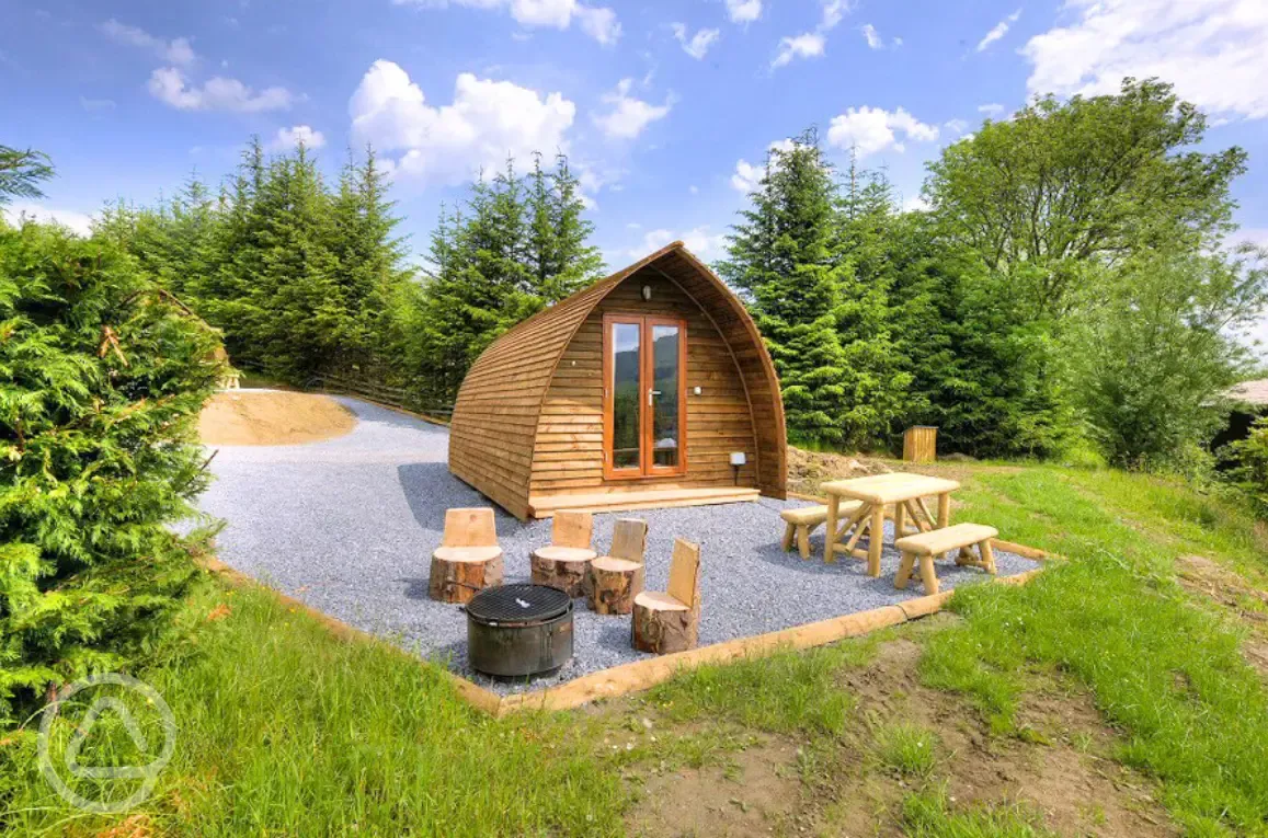 Premium ensuite glamping pods with picnic bench and wood carved stools
