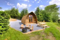 Premium ensuite glamping pods with picnic bench and wood carved stools