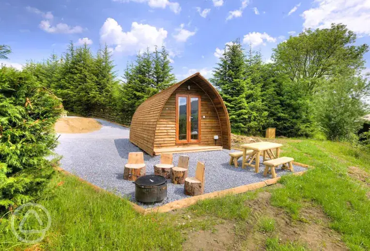 Premium ensuite glamping pods with picnic bench and wood carved stools