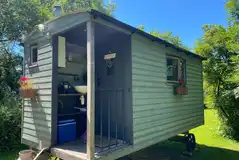 Shepherd's Hut exterior with private decking with a fire pit and BBQ