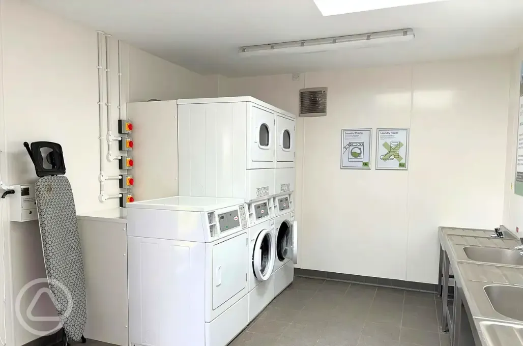 Laundry area with washing machines, tumble dryers, and ironing boards Laundry area with washing machines, tumble dryers, and ironing boards