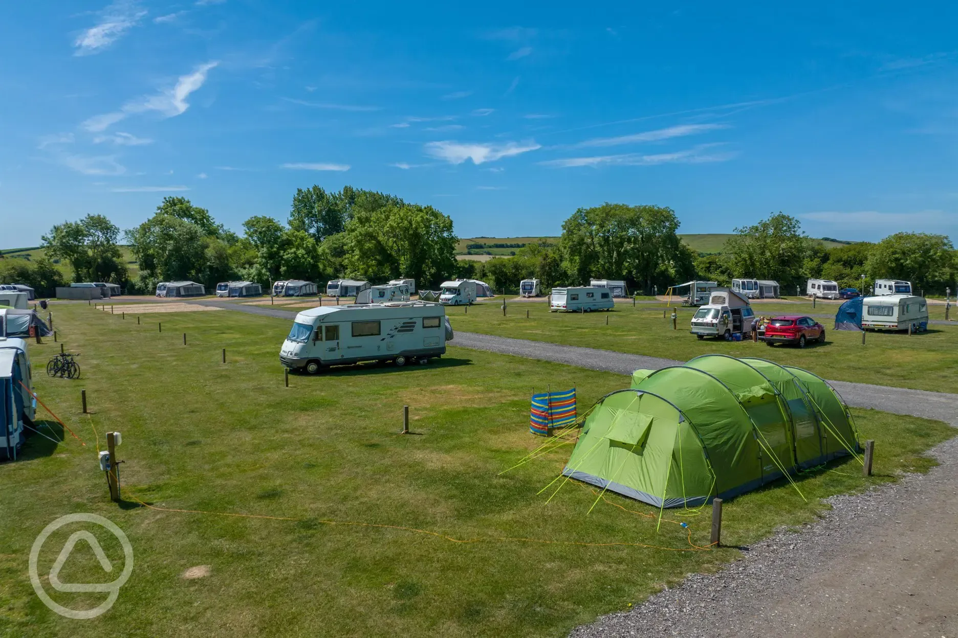 Grass pitches welcoming tents and tourers, some with electric hook ups