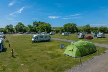 Grass pitches welcoming tents and tourers, some with electric hook ups