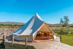 Bell tent on a decking area with a picnic bench