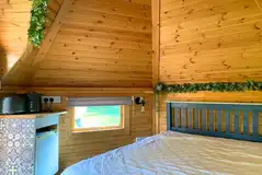 Hexi glamping pod interior with bed, heater, fridge, kettle, toaster and TV