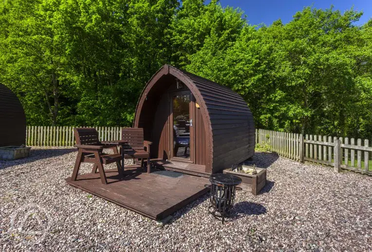 Camping pod with decking, chairs, and a fire pit