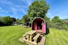 Wooden colourful camping pods with outdoor decks and picnic benches Wooden colourful camping pods with outdoor decks and picnic benches
