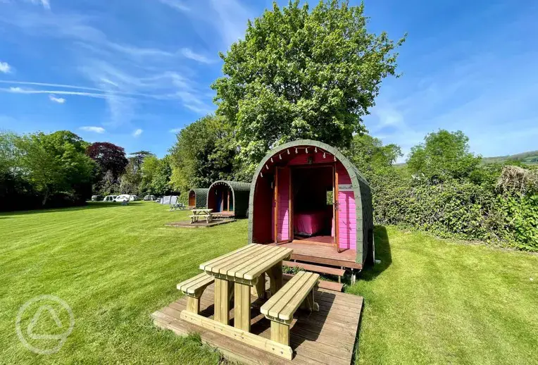 Wooden colourful camping pods with outdoor decks and picnic benches