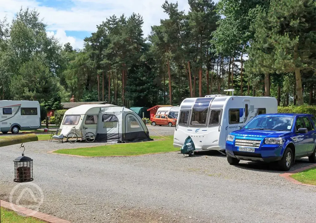 Electric hardstanding and grass pitches with a car parked beside pitch