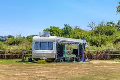 Caravan with an awning on an electric grass pitch Caravan with an awning on an electric grass pitch