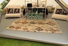 Bell tent interior with a double bed and two futons Bell tent interior with a double bed and two futons