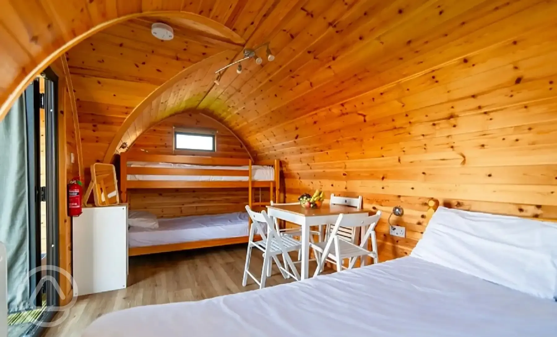 Dog friendly camping pod interior with double bed, bunk beds and table