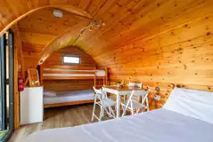 Dog friendly camping pod interior with double bed, bunk beds and table