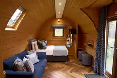 Kitchenette, sofa, and double bed in the deluxe mega pod (bedding provided)