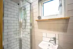Shepherd's hut ensuite with a toilet, hand basin, shower, towels and toiletries