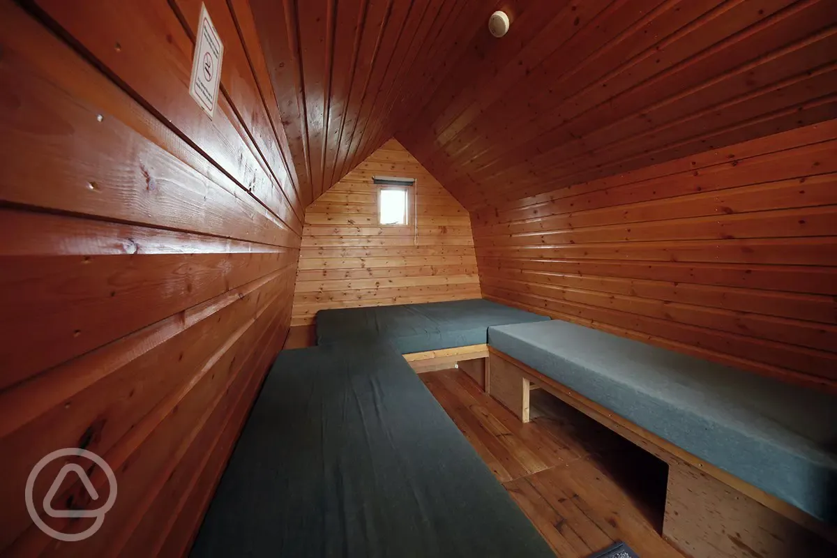 Camping pod interior with bench-style mattresses