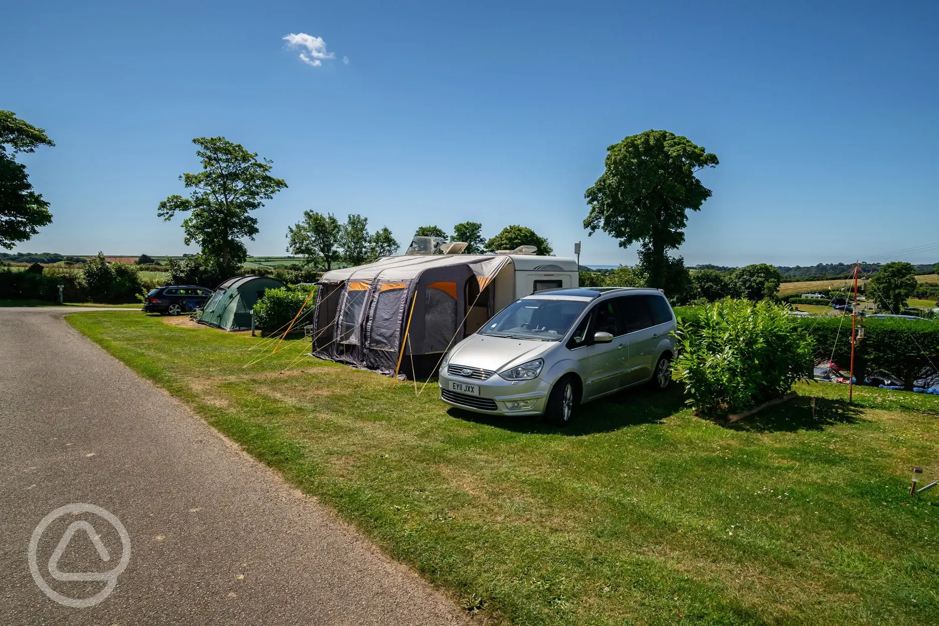 Caravan and awning on grass pitches at Tregarton Park with car parking space