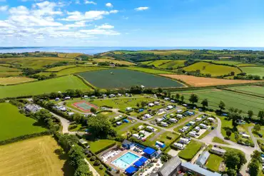 Aerial of Tregarton Park with outdoor pool, tennis courts, and sea views