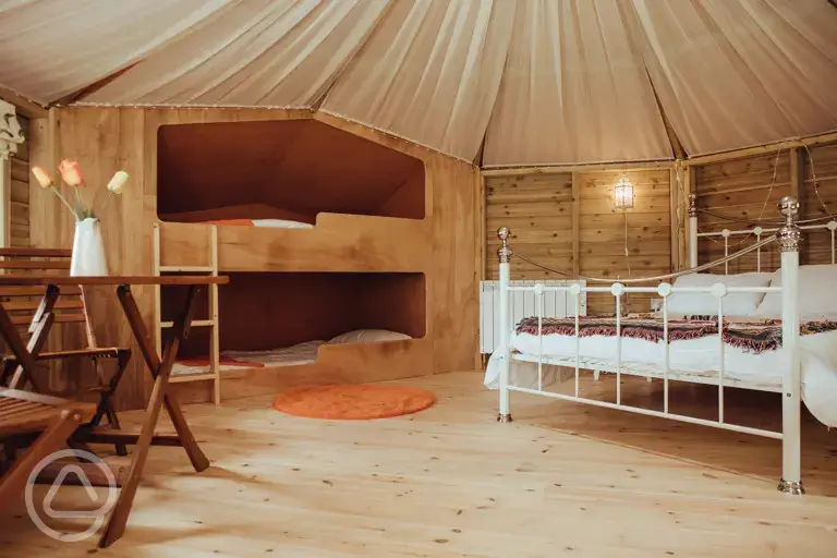 Glamping cabin interior with a double bed and two single bunk beds