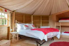 Glamping cabin interior with a double bed and two single bunk beds