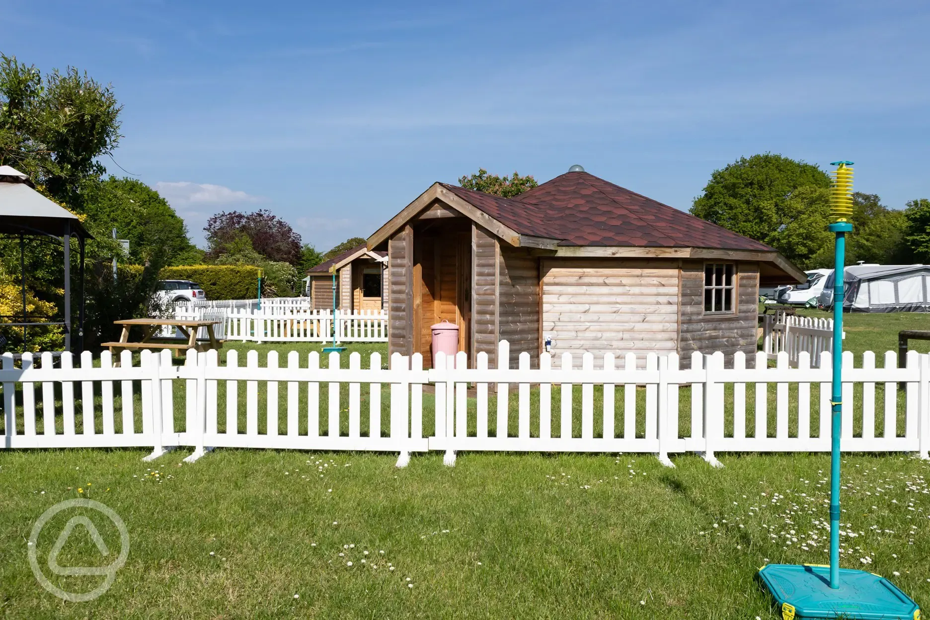 Fenced glamping cabins with a swing ball and a picnic bench