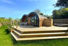 Glamping pod lodge with a large wrap-around deck with a hot tub