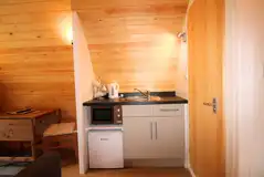 Ensuite glamping pod kitchen with a fridge, kitchen sink, kettle, microwave