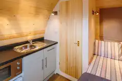 Ensuite pod bed and kitchen with a fridge, kitchen sink, kettle, microwave