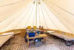 Bell tent interior with a double bed and two camp beds (bedding included)