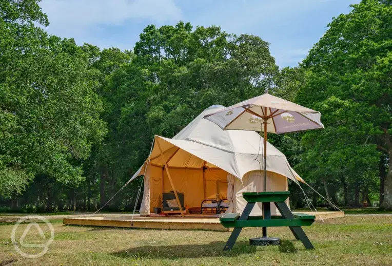 Furnished bell tent on a raised platform with a picnic bench