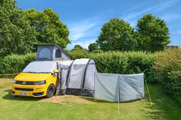 VW campervan and awning on an electric grass pitch