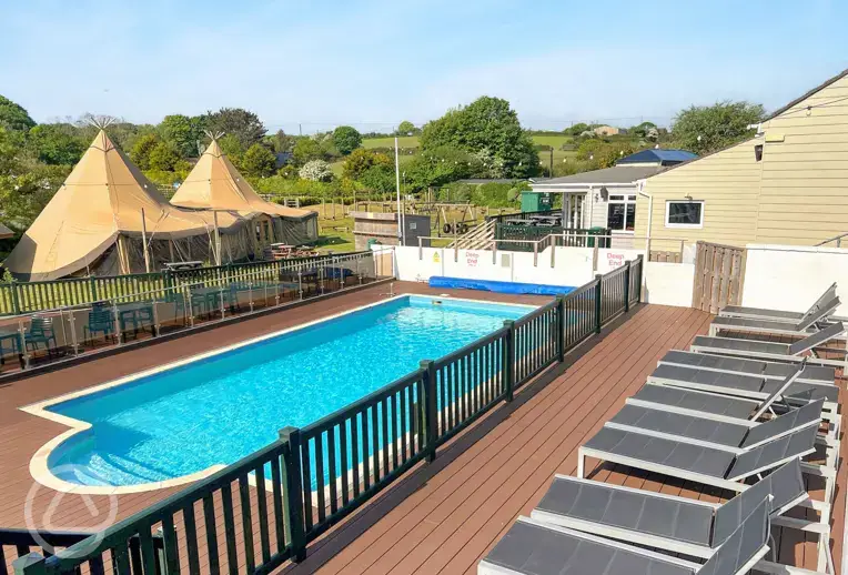 Outdoor heated swimming pool at Calloose Holiday Park with sun loungers