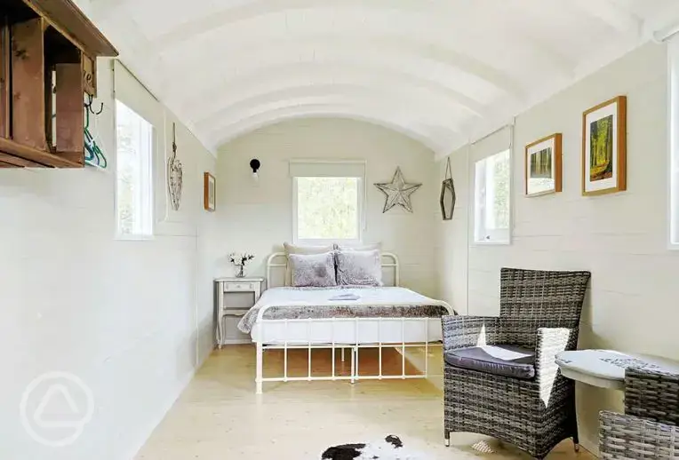 Shepherd's hut with a double bed and seating area