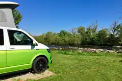 VW campervan on a riverside electric hardstanding pitch at Sleningford Watermill