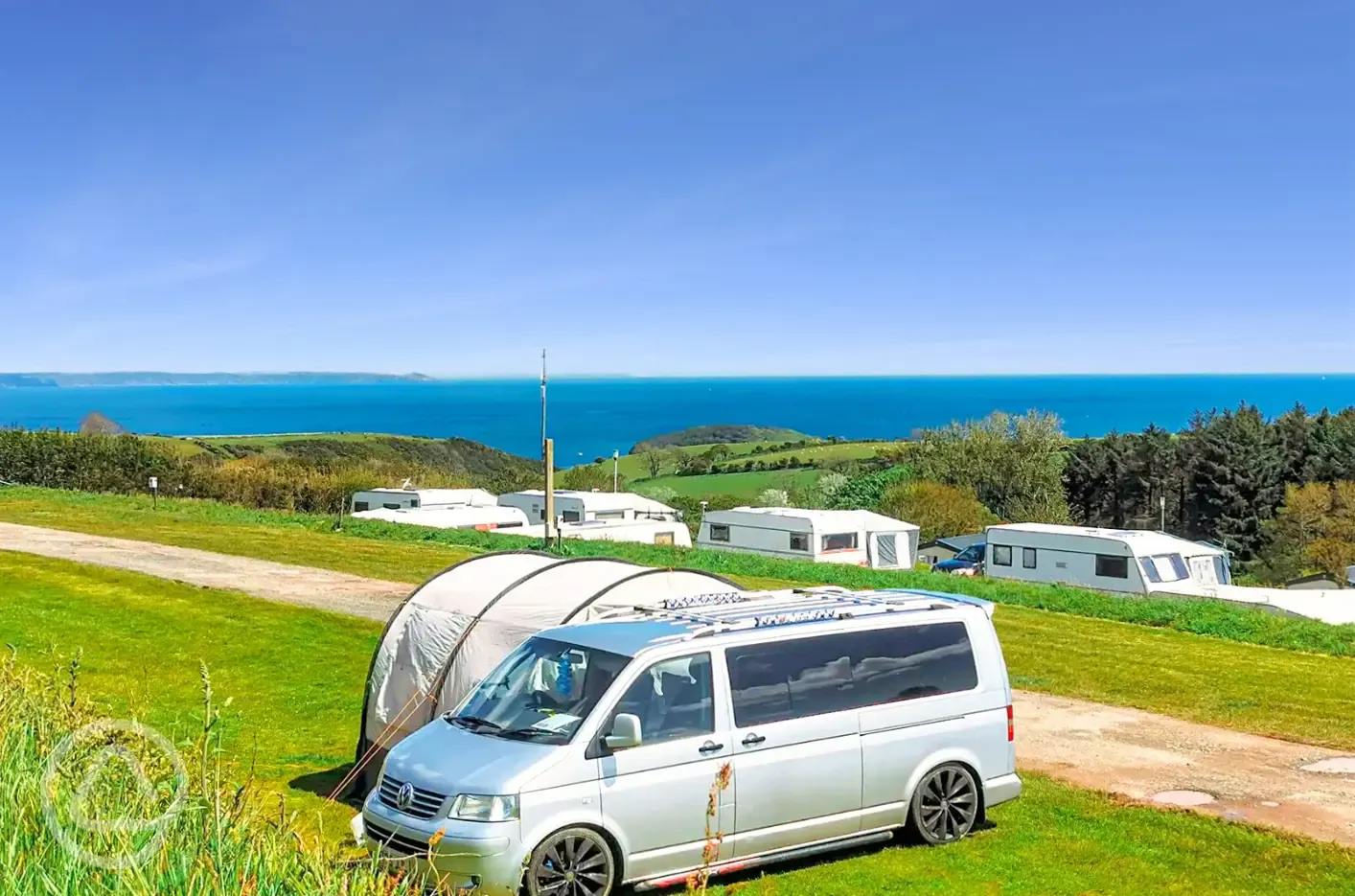 Grass pitches at Tencreek Holiday Park with views towards the sea