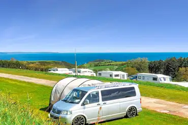 Grass pitches at Tencreek Holiday Park with views towards the sea