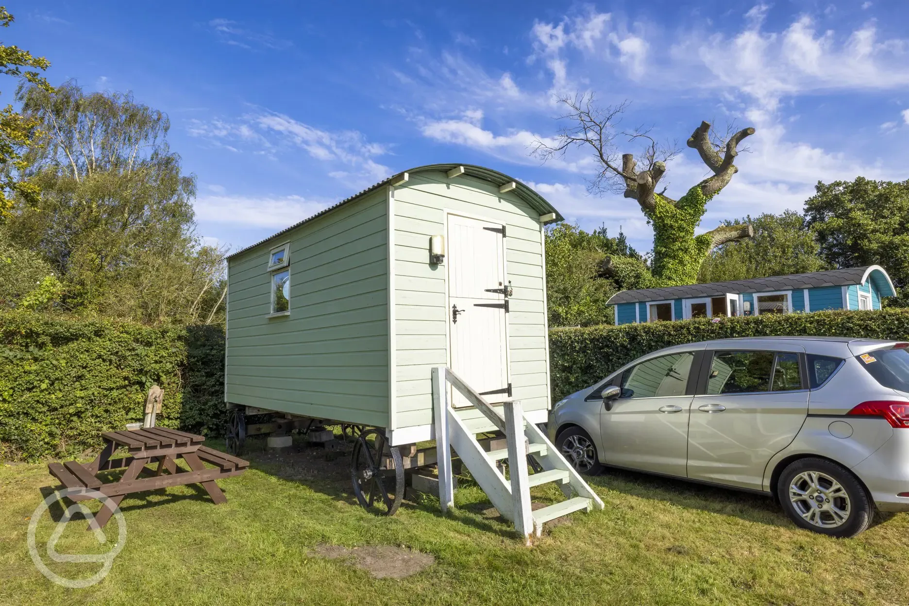 Green shepherd's hut with outdoor picnic bench