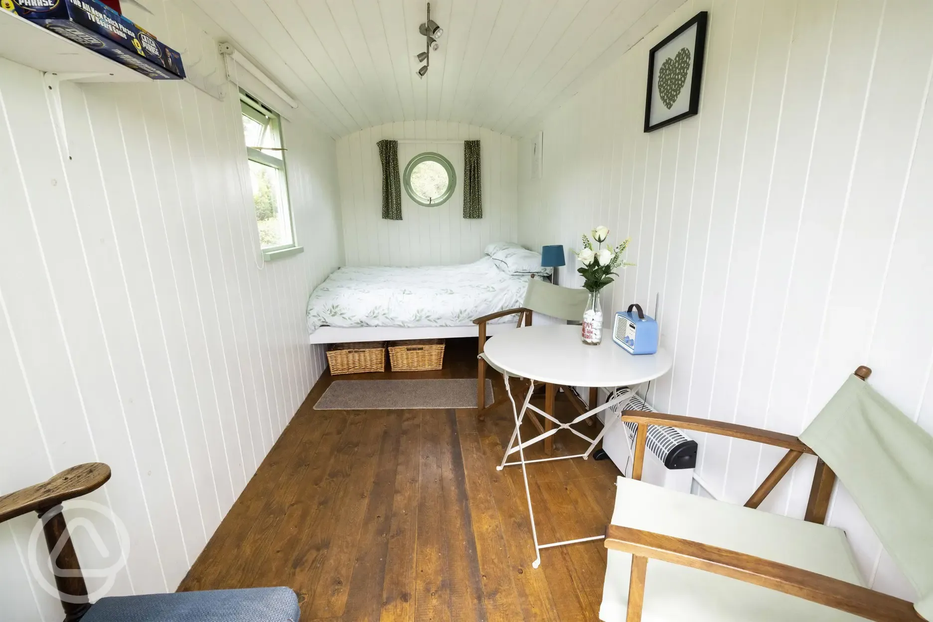 Green shepherd's hut interior with double bed and seating