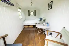 Green shepherd's hut interior with double bed and seating