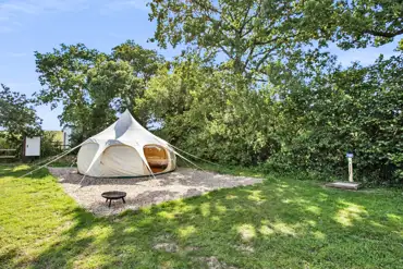 Furnished bell tent on gravel with a fire pit