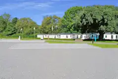 Fully serviced hardstanding pitches with static caravans behind Fully serviced hardstanding pitches with static caravans behind
