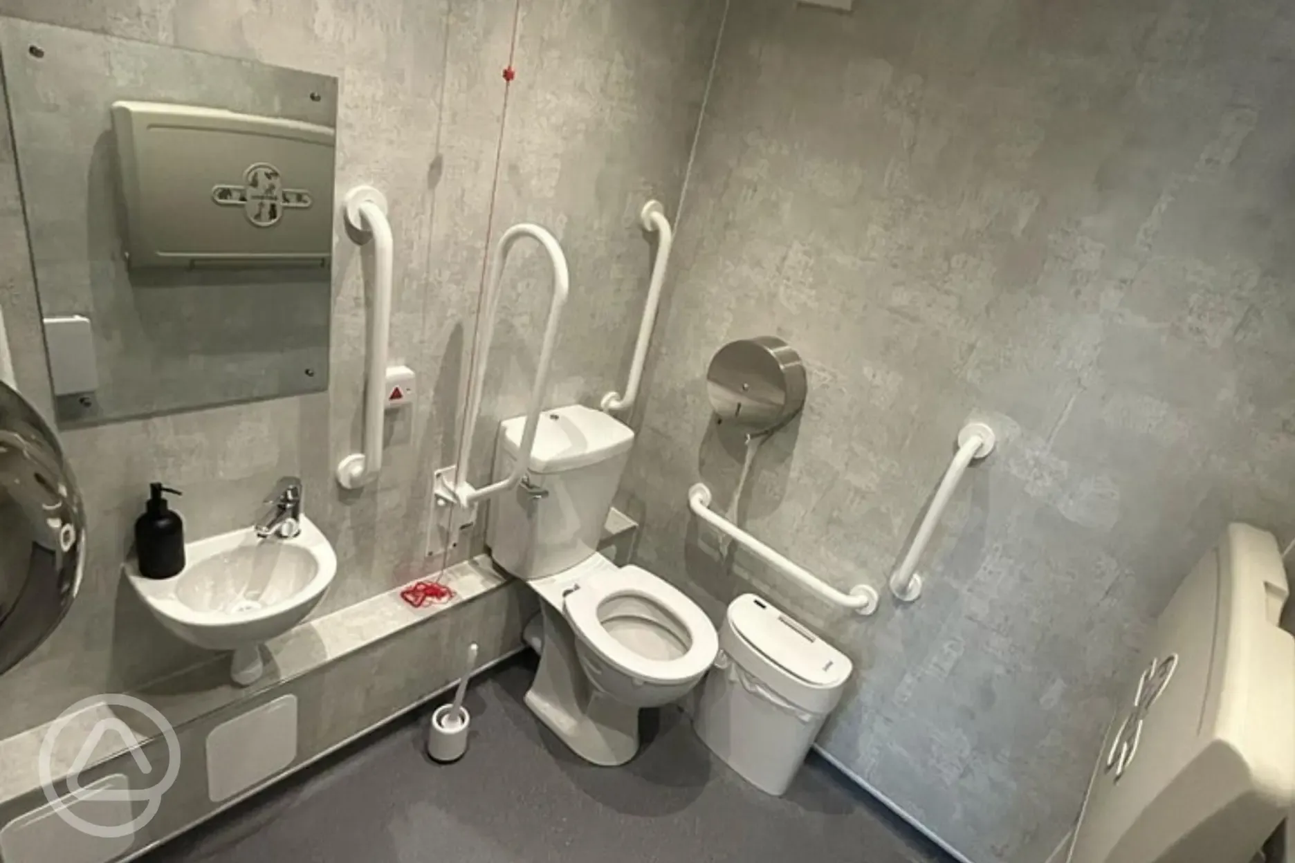 Accessible bathroom featuring grab rails and a baby change area Accessible bathroom featuring grab rails and a baby change area