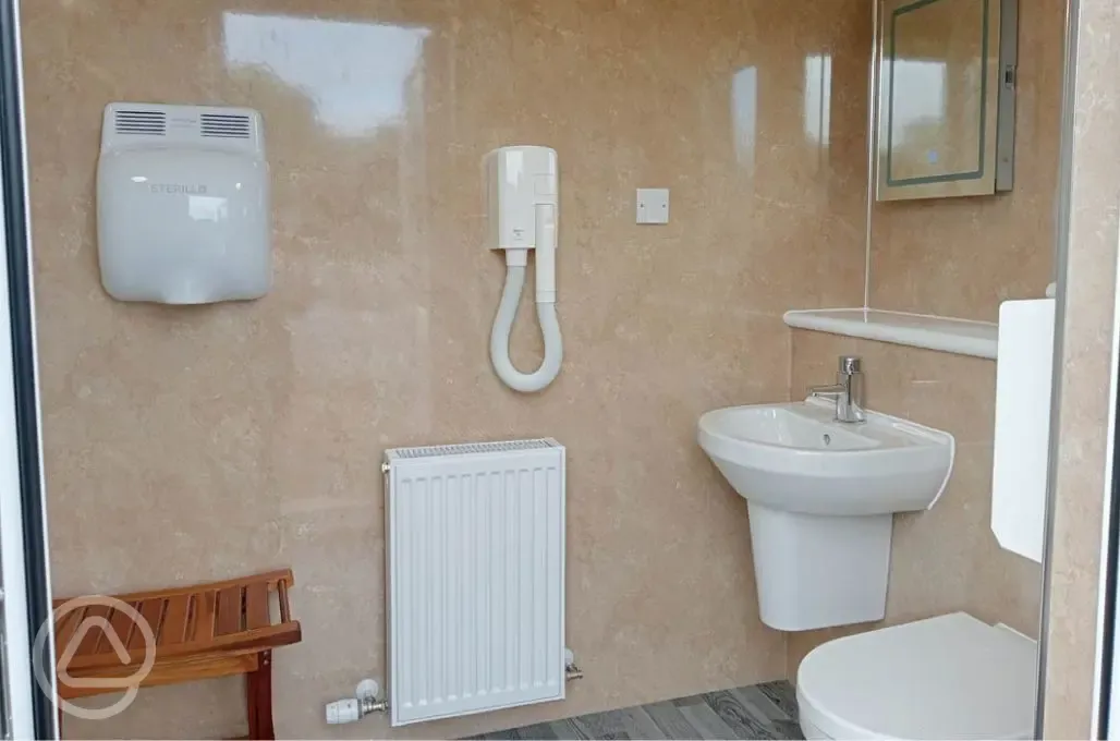 Shared bathroom with a toilet, sink, hand dryer, and mirror Shared bathroom with a toilet, sink, hand dryer, and mirror