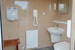 Shared bathroom with a toilet, sink, hand dryer, and mirror Shared bathroom with a toilet, sink, hand dryer, and mirror