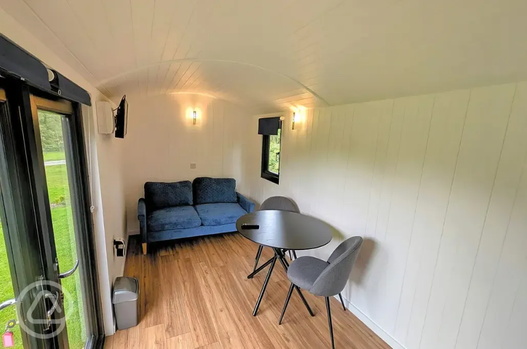Shepherd's hut interior with a sofa/futon, table, and chars