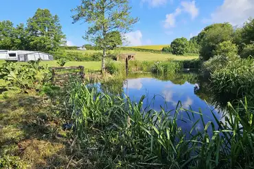 Onsite lake at Pensagillas Park with distant views of the touring pitches