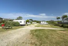 Electric hardstanding pitches with picnic benches, separated by hedging