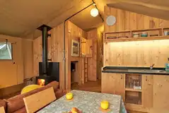 Safari tent lounge, dining and kitchen area with a wood burner