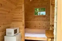 Small pod interior with a double bed, fridge and microwave