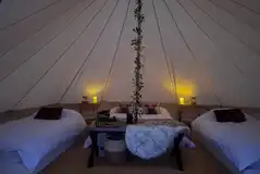 Bell tent interior furnished with a double and two single beds